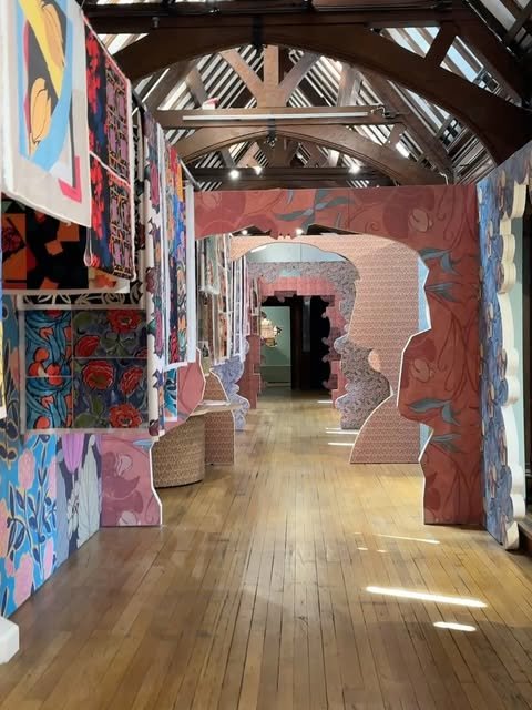 Liberty London textile floor with timber roof trusses, hanging fabrics, and a patterned archway.
