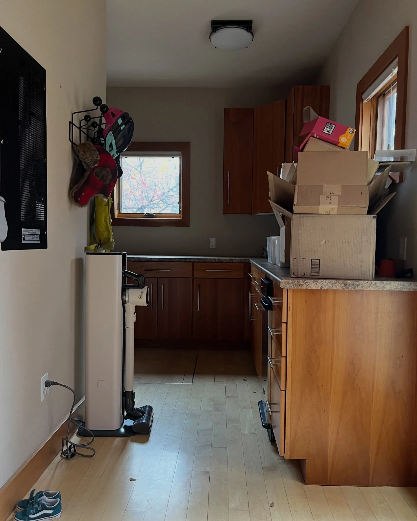 Existing utility room with wood cabinetry, a small window, and a tiled floor before renovation.