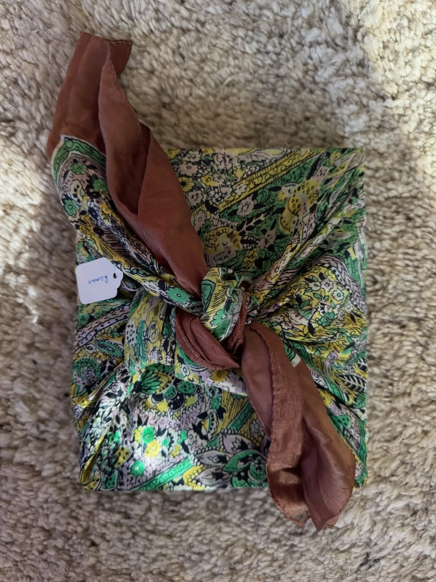 Gift wrapped in a floral fabric and tied with a contrasting rust-colored textile.