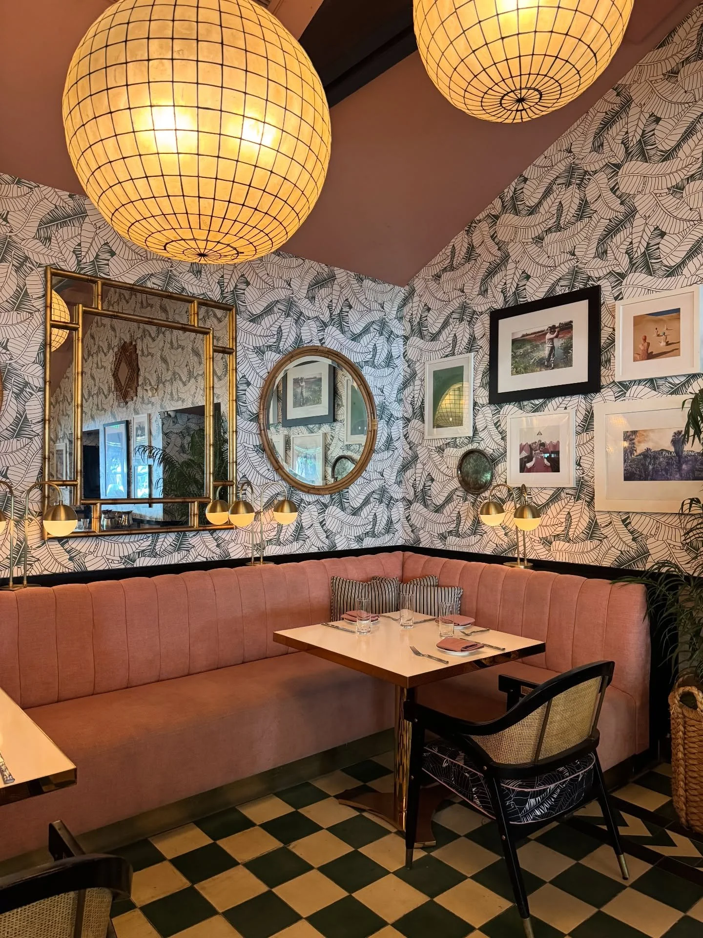 Palm Springs restaurant booth with woven pendants, framed art, and green-and-cream floor tile.