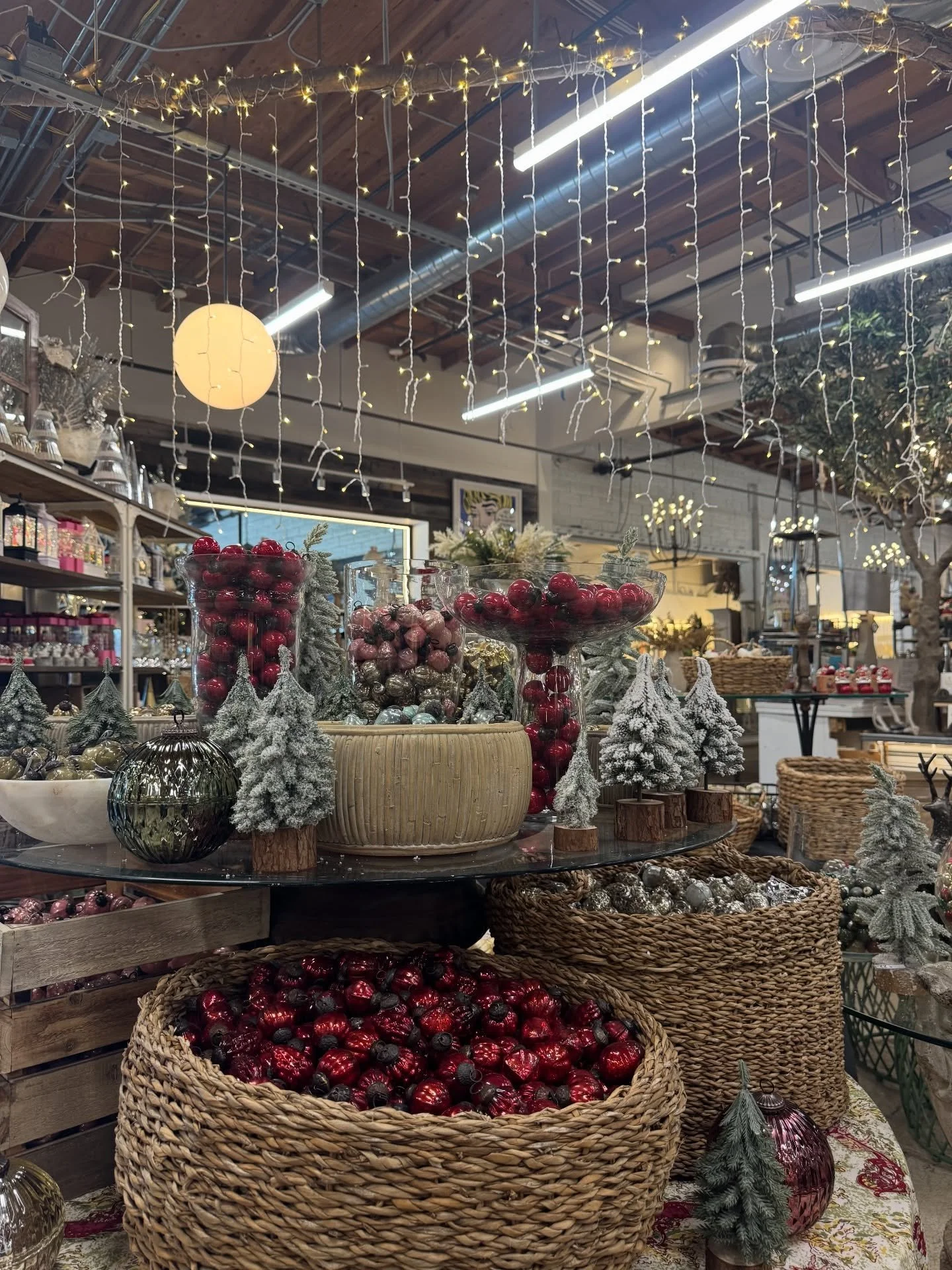 Shop display with branches, baskets, ornaments, and overhead globe lighting.