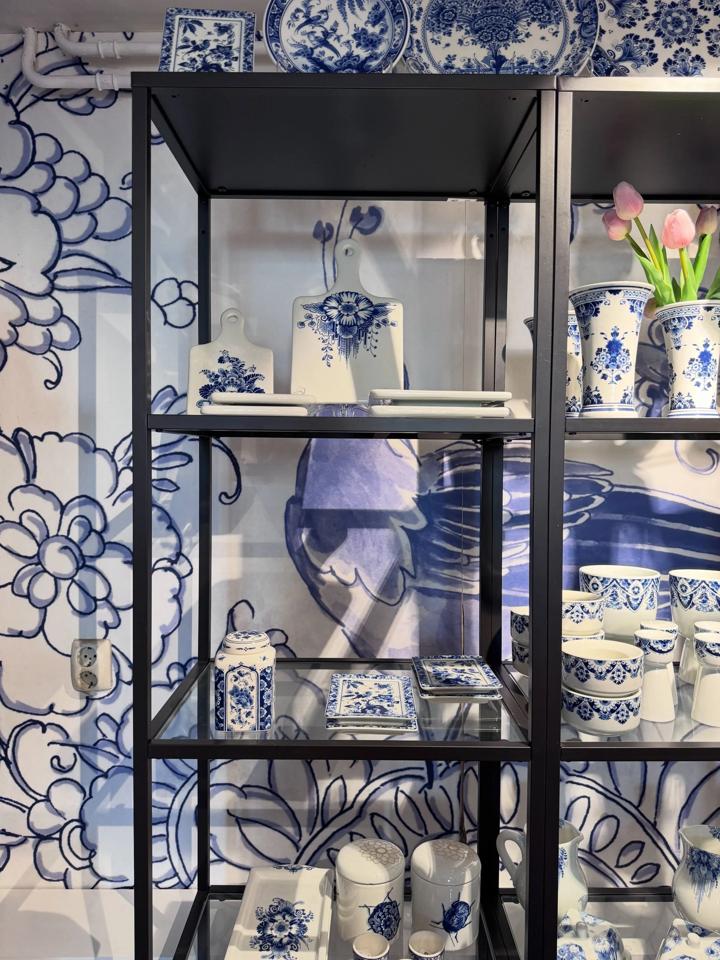 Delft Blue ceramics displayed against blue-and-white patterned walls.