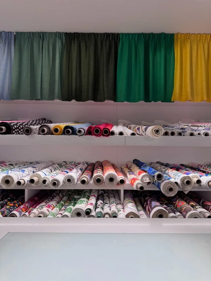 Fabric rolls and a row of green and yellow hanging textile samples at Svenskt Tenn.
