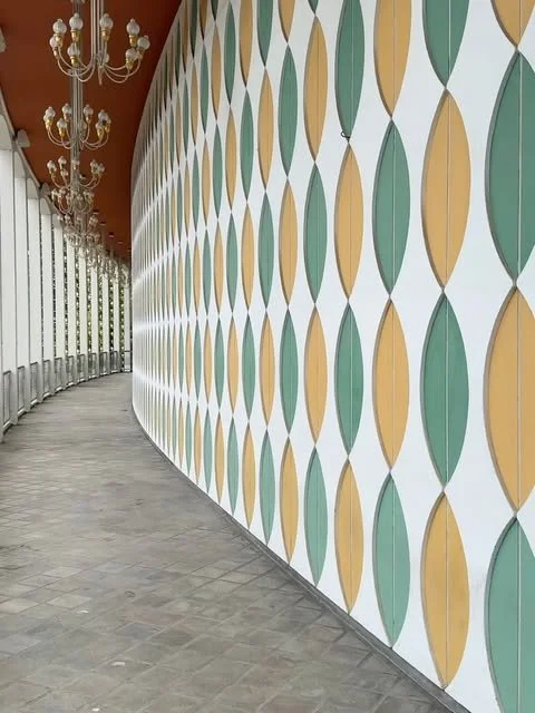 Curved Tivoli wall painted with repeating green, yellow, and white geometric forms.