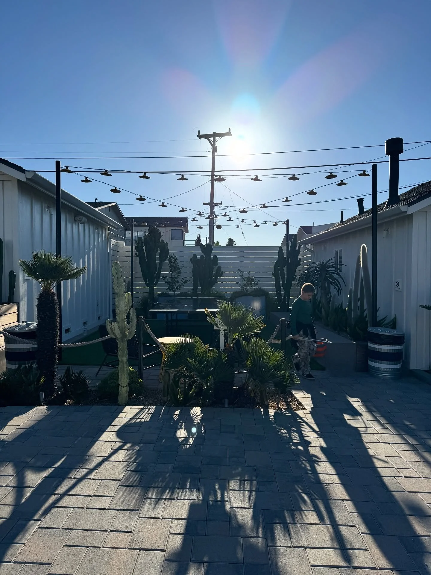 Pacific Motel courtyard with white timber buildings, outdoor chairs, and string lights.