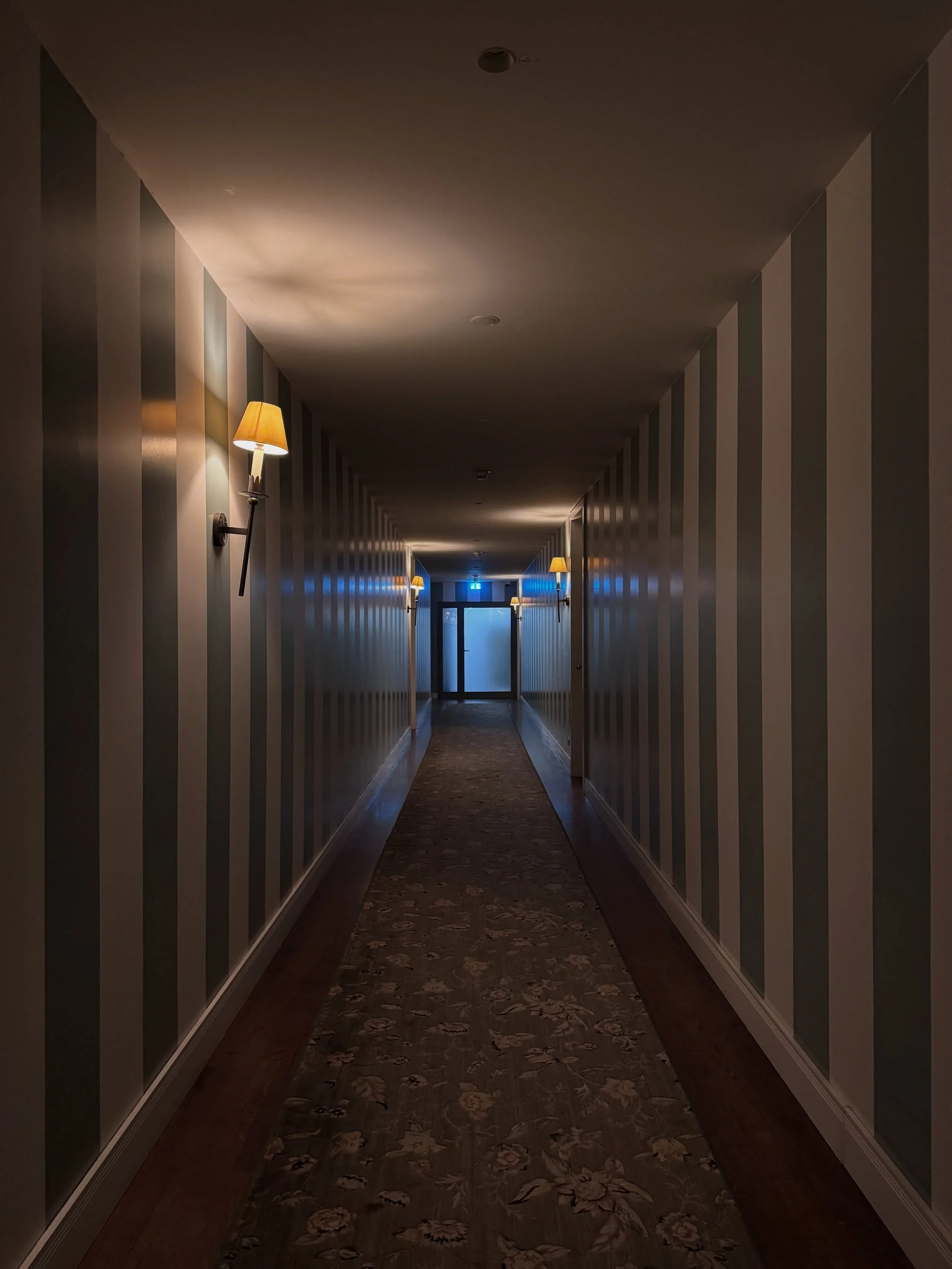 Dimly lit hotel corridor with paneled walls and warm wall lights at Soho House Berlin.