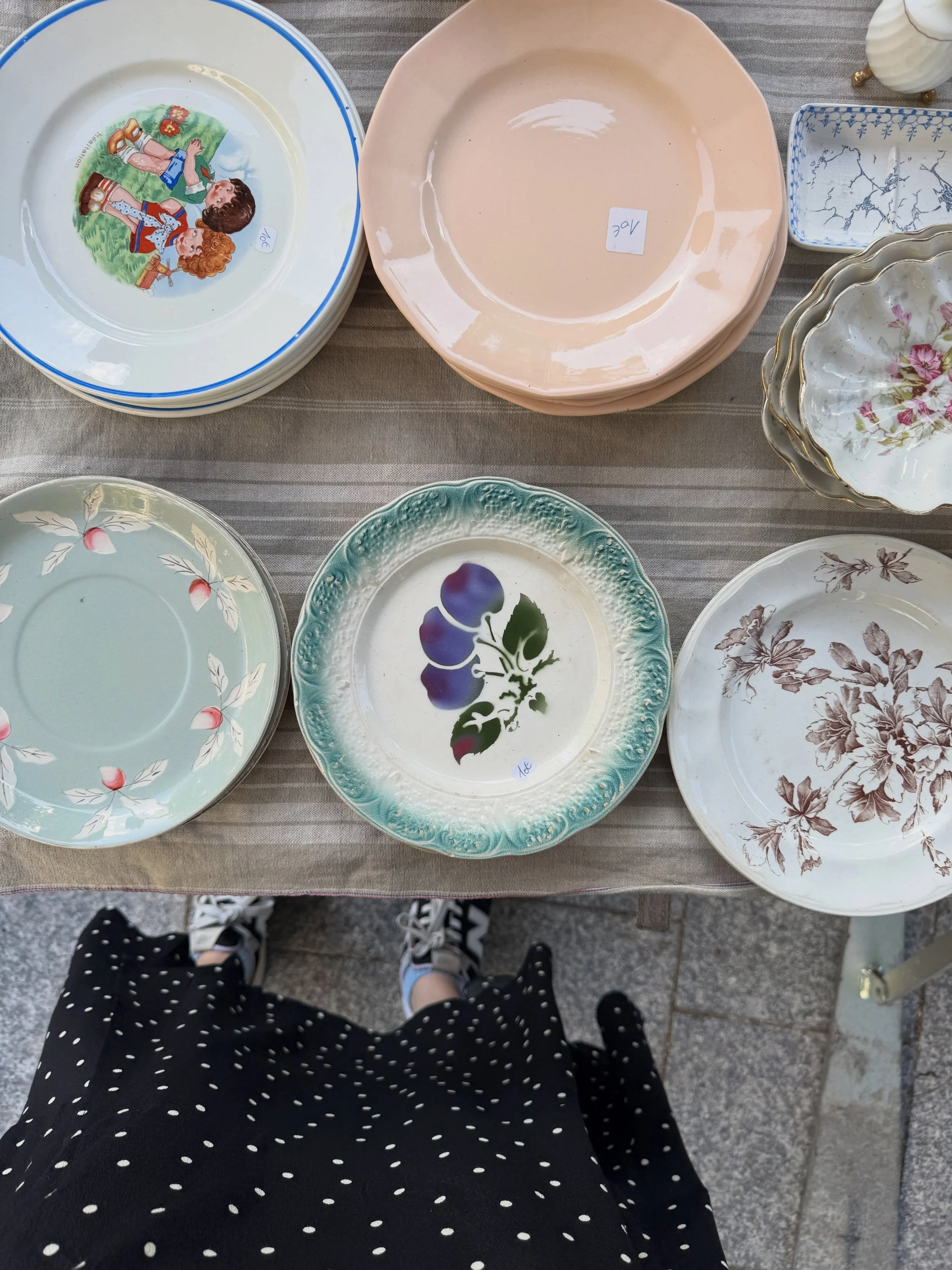 Vintage floral plates and pastel ceramic dishes at a Paris flea market.