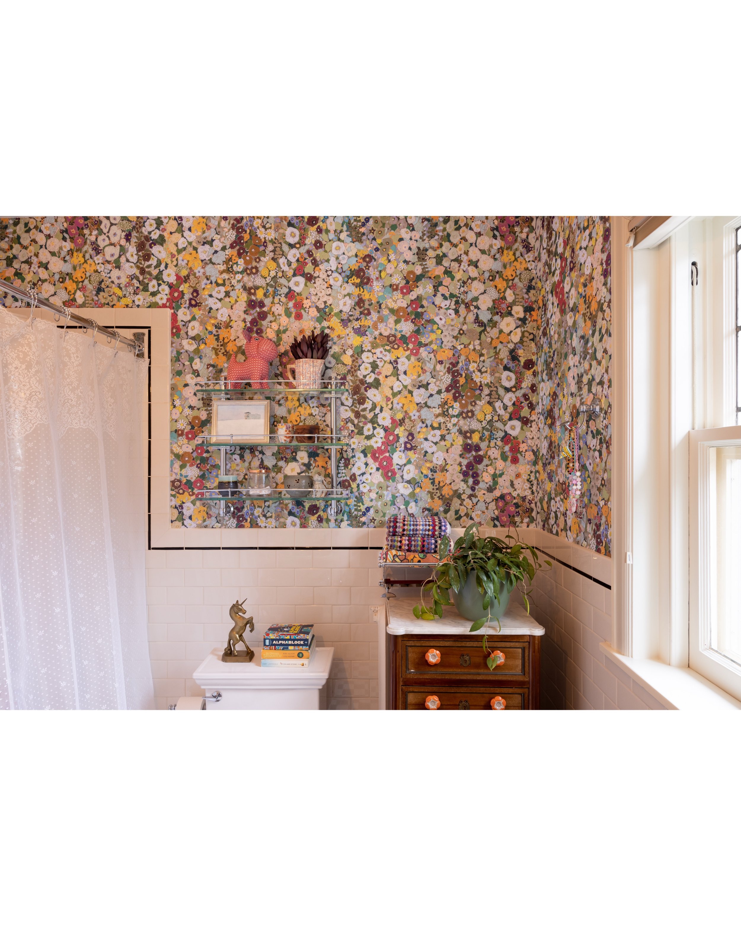 Floral-wallpaper powder room with a pale counter, window, and wood cabinet.