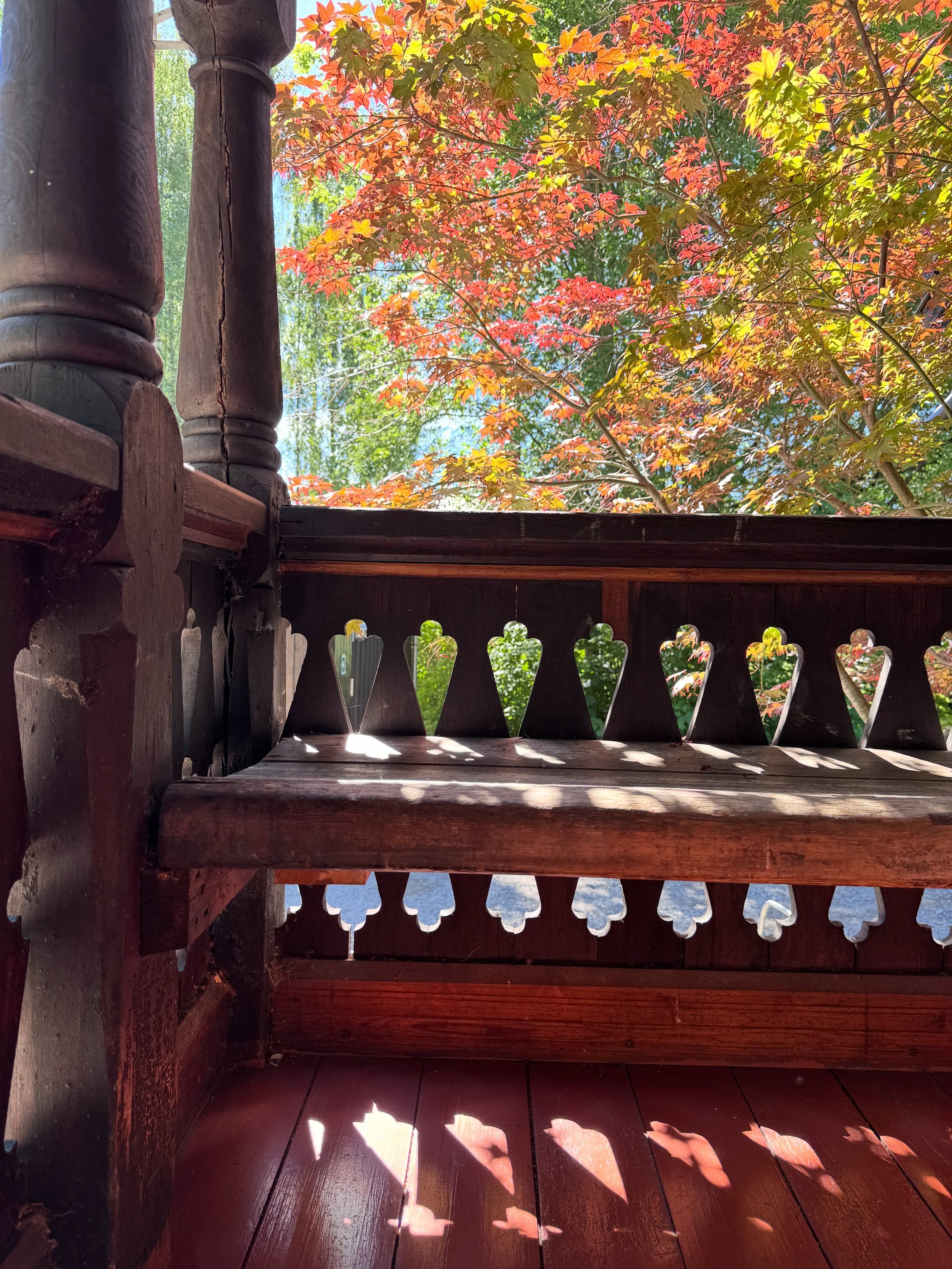 Carved timber balcony with a red railing and decorative openings in Oslo.