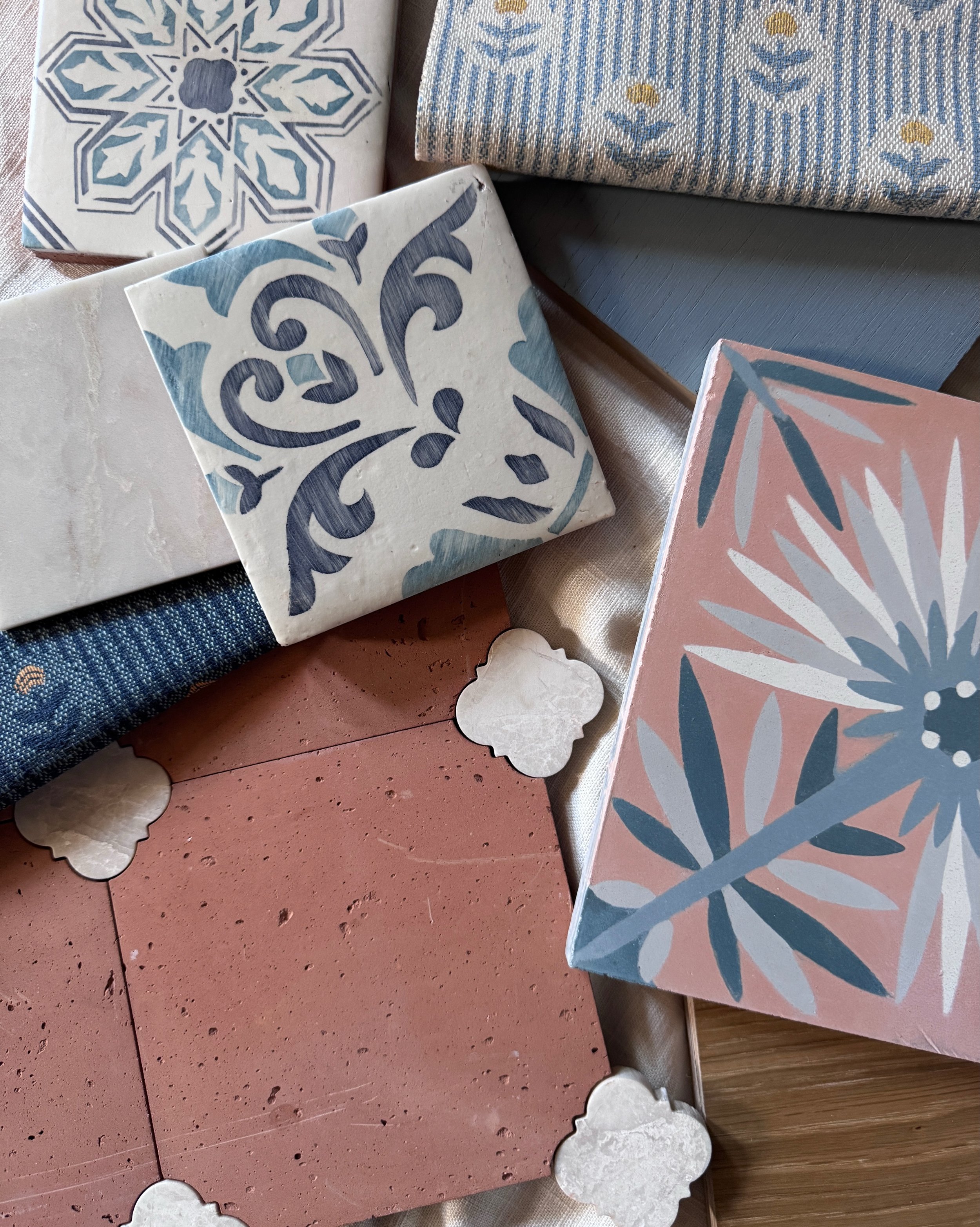 Design samples with blue-and-white patterned tile, dusty pink tile, woven textiles, and wood.