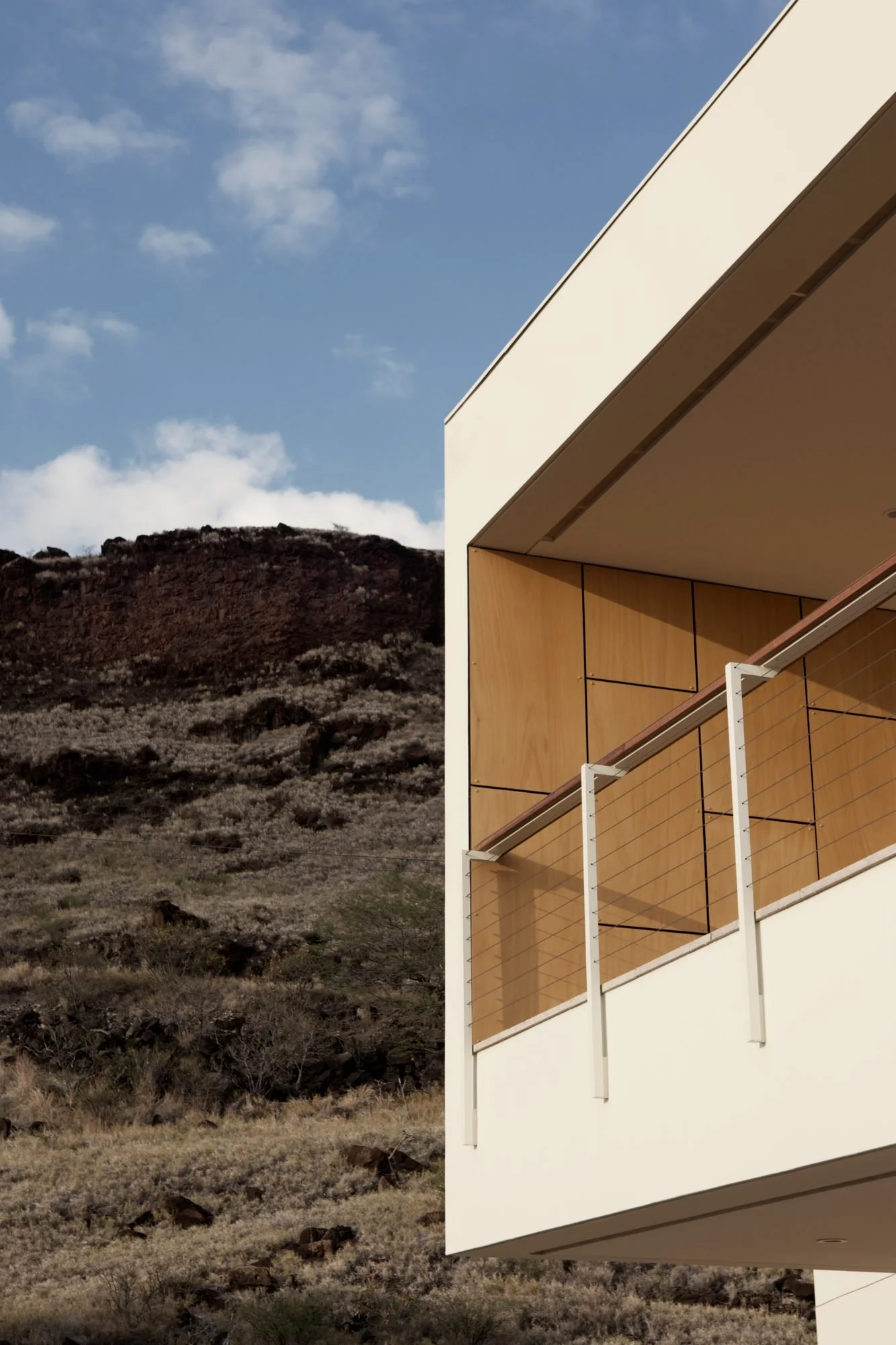 Cantilevered lānai with wood screen against dry red cliffs