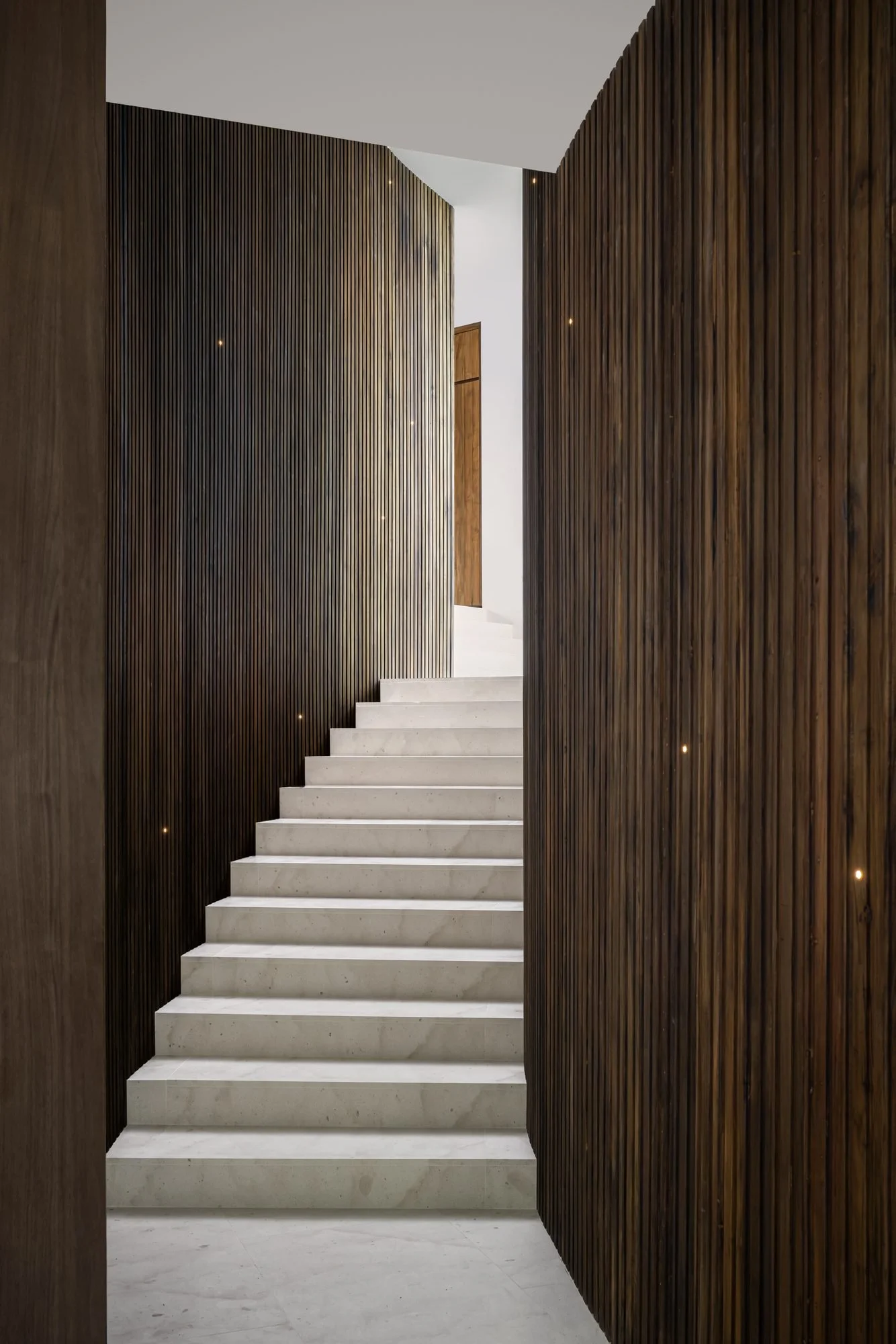 Pale stone stair rising between two dark wood walls