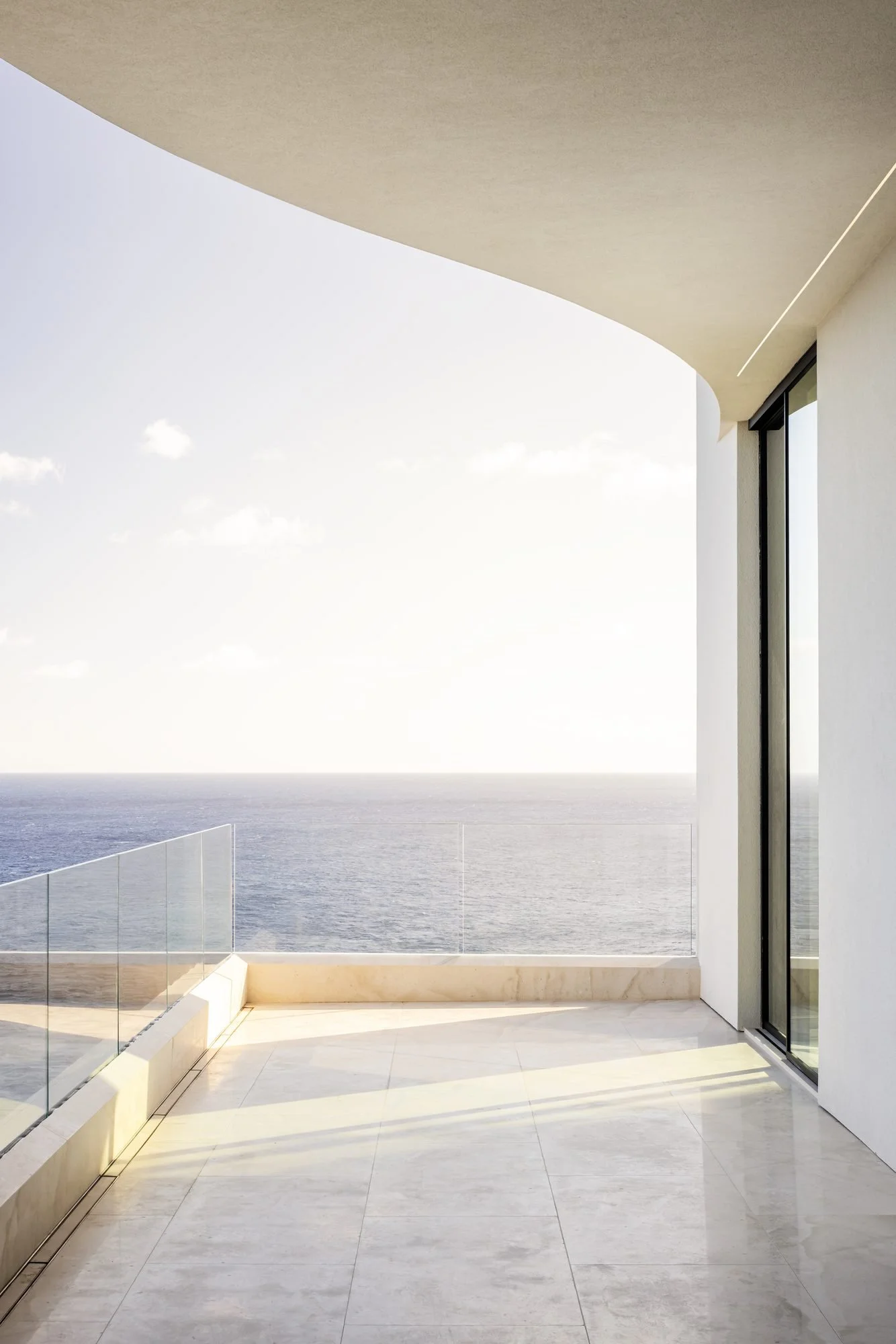 Curved soffit over a stone lānai and the open horizon