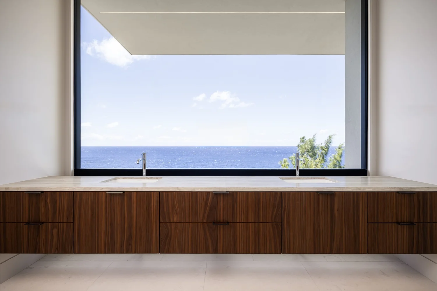 Walnut vanity beneath a wide window framing the ocean