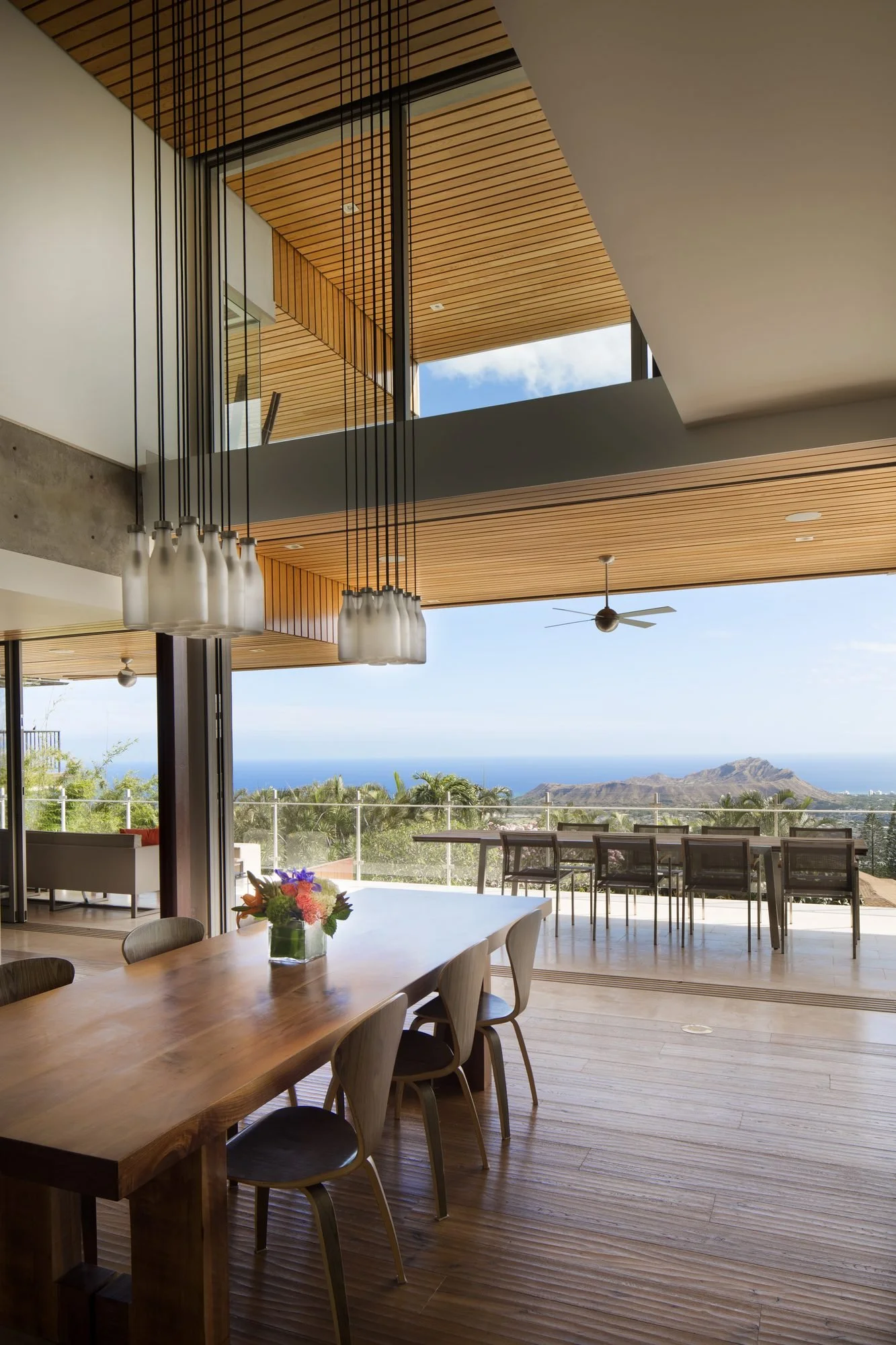 Double-height dining room opening onto a lānai with Diamond Head and the ocean beyond