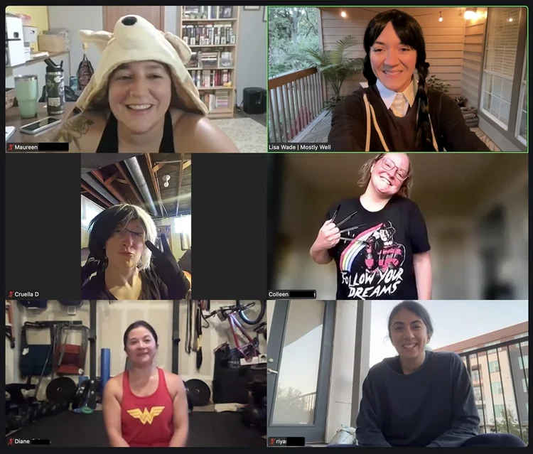 Video call grid of Coach Lisa and members in Halloween costumes during a live workout