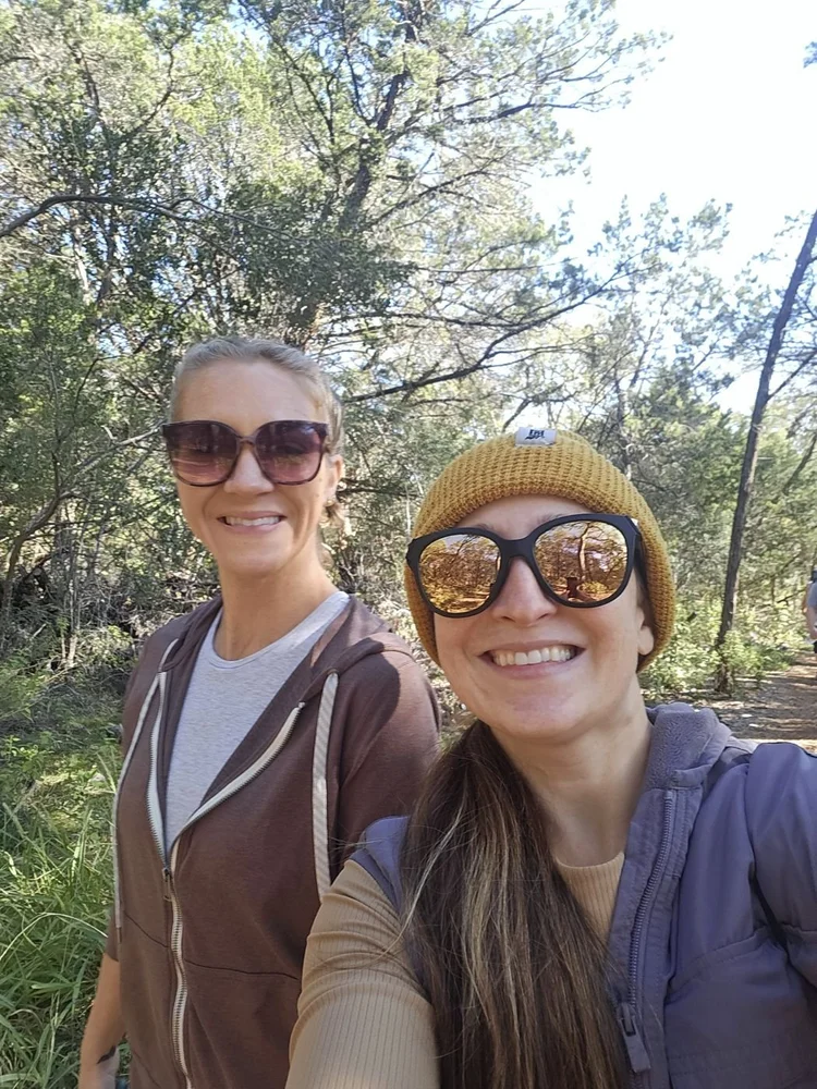Two walkers in sunglasses smiling on a sunny Hill Country trail