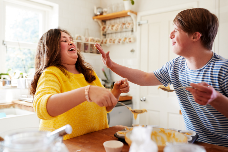 Young couple with Down syndrome cooking in the kitchen and laughing