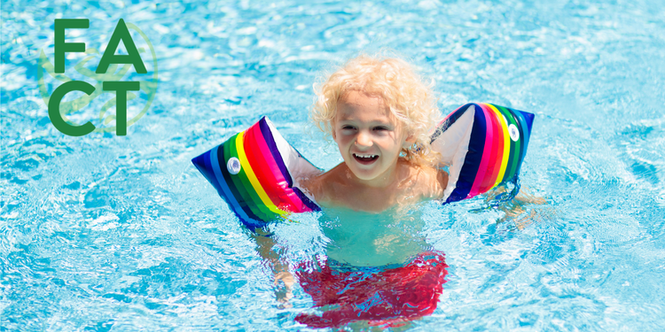 A child uses rainbow-colored float aids to swim in a pool