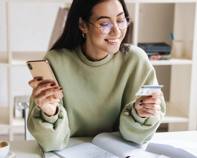 A teenage girl holds a debit card and calculator