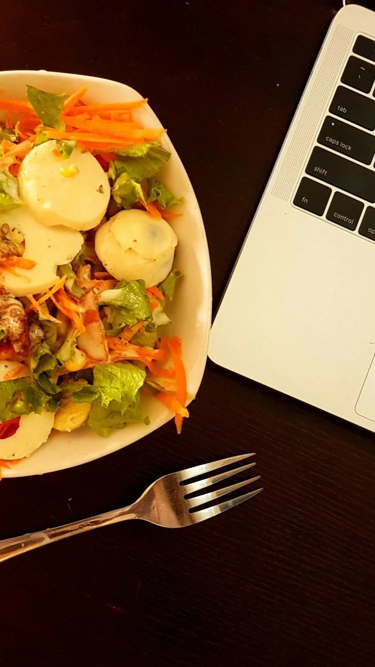 A plate of food, a fork, and a laptop