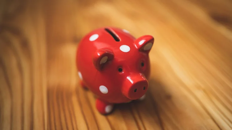 a red polka dot piggy bank rests on a wood floor