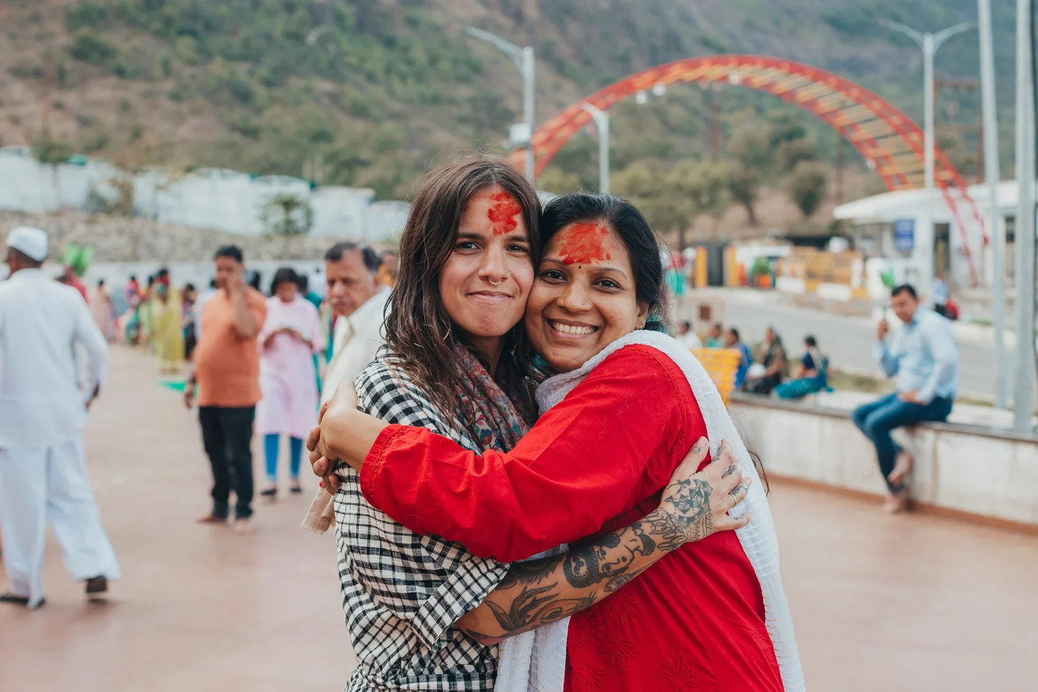 Adriana Rizzolo and Dr. Varsha Choudhari embracing cheek to cheek and smiling, both with red kumkum on their foreheads, at a temple in India