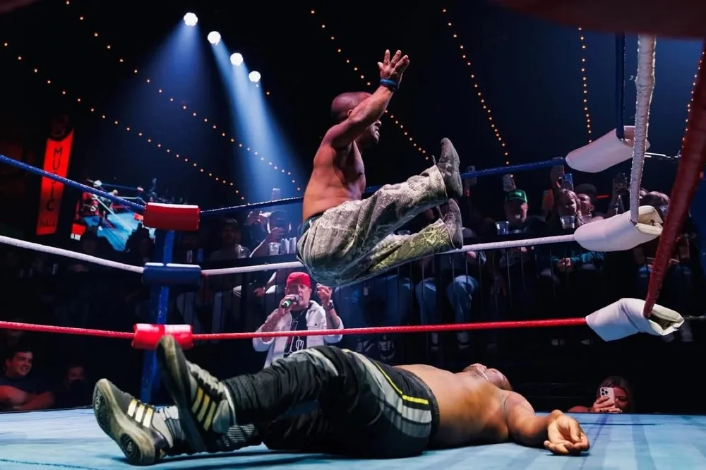 A wrestler leaps from the top rope