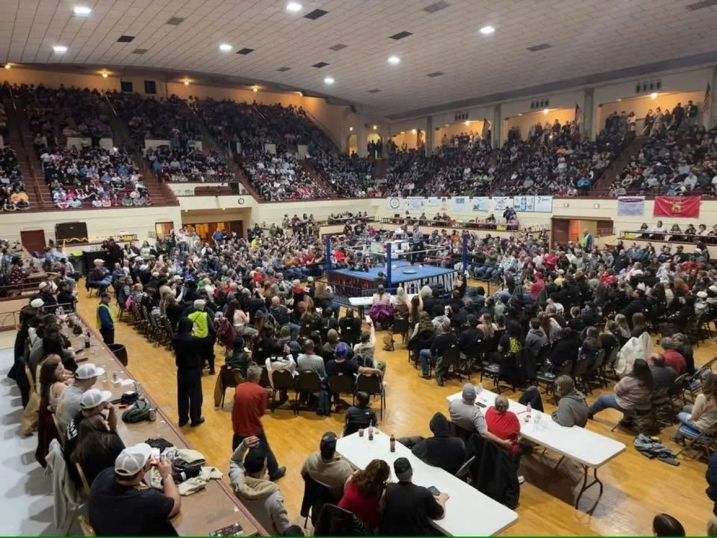 An arena floor full of fans around the ring
