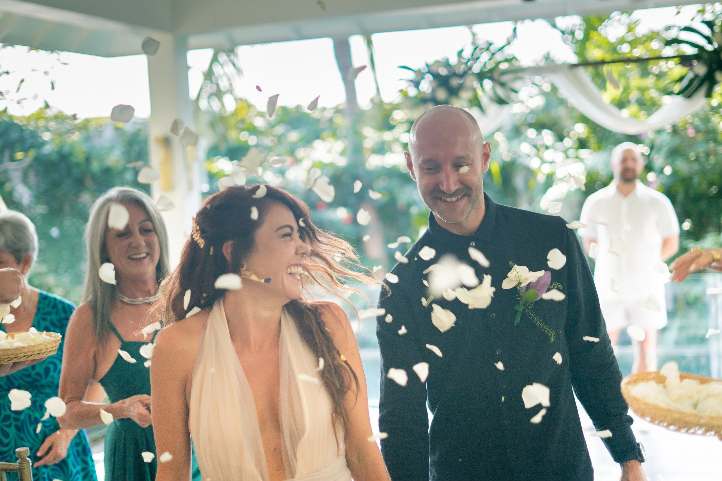 A joyful couple walking through a shower of flower petals