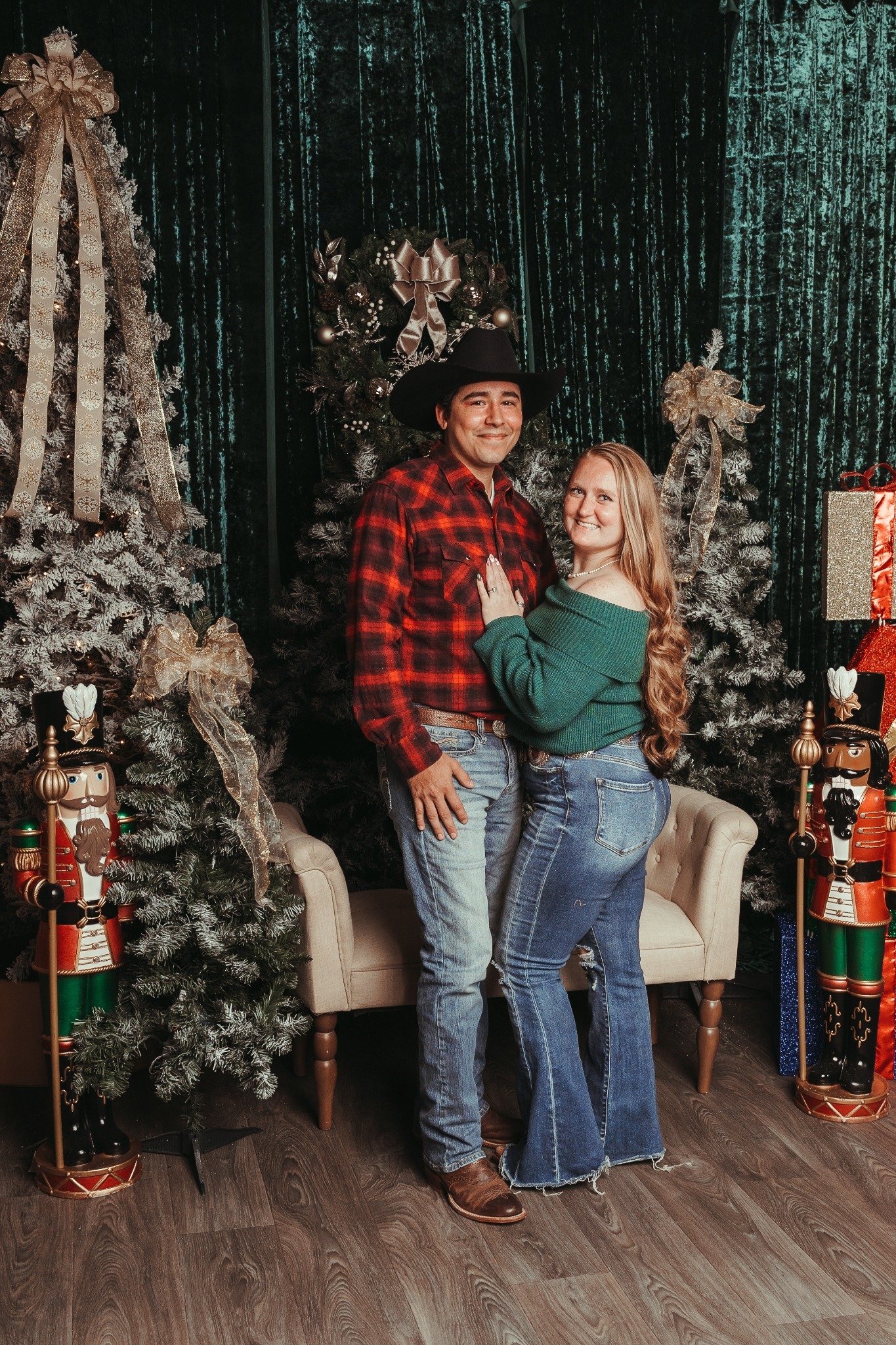 Couple standing together beside a frosted Christmas tree