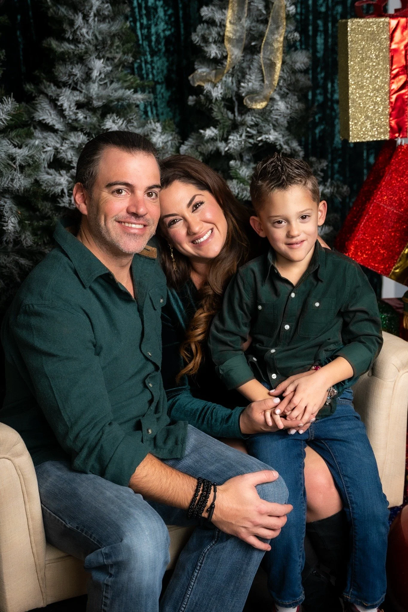 Family in green smiling beside a Christmas tree