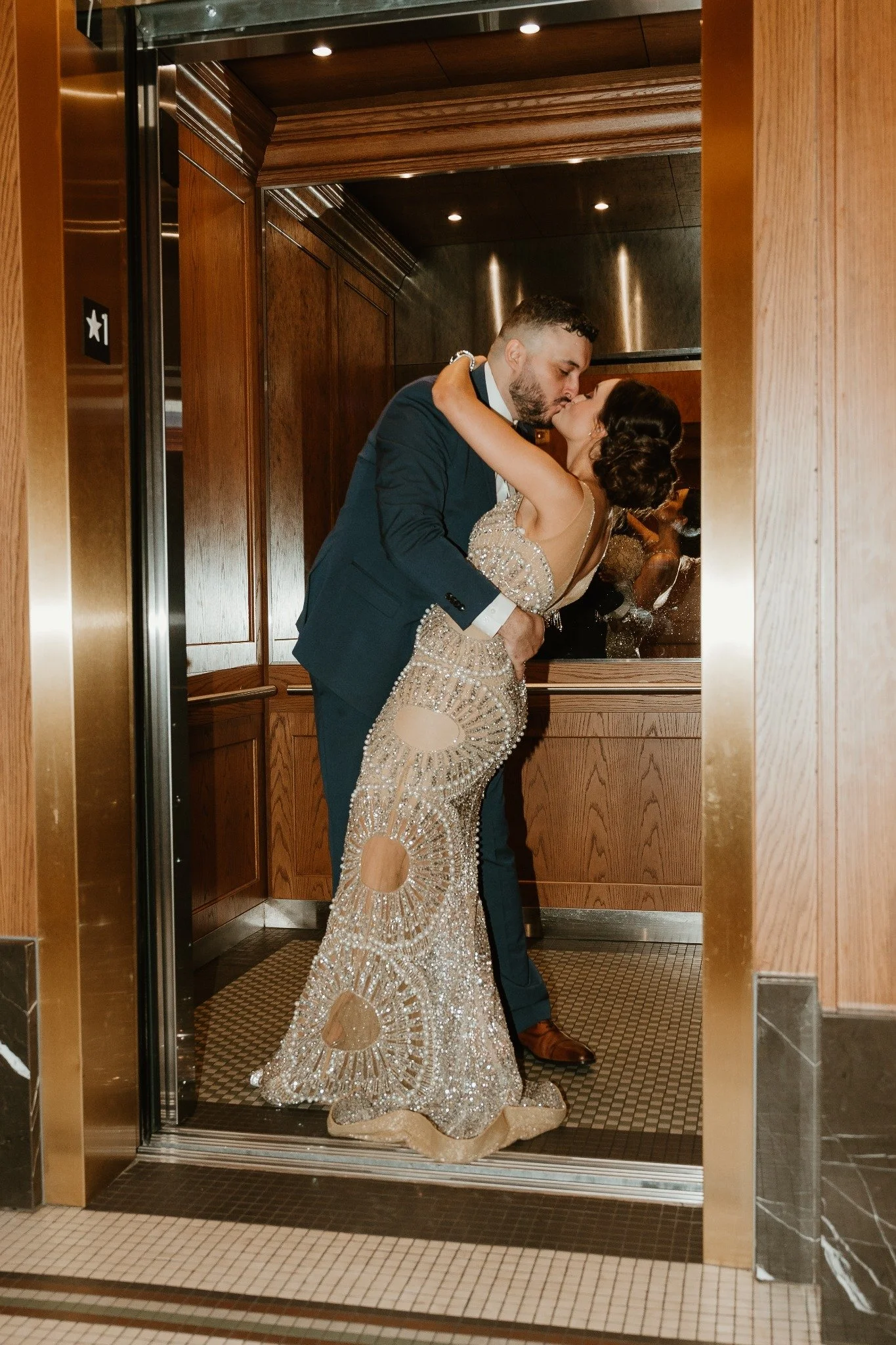 A couple embracing on a wooden staircase in formal evening attire.