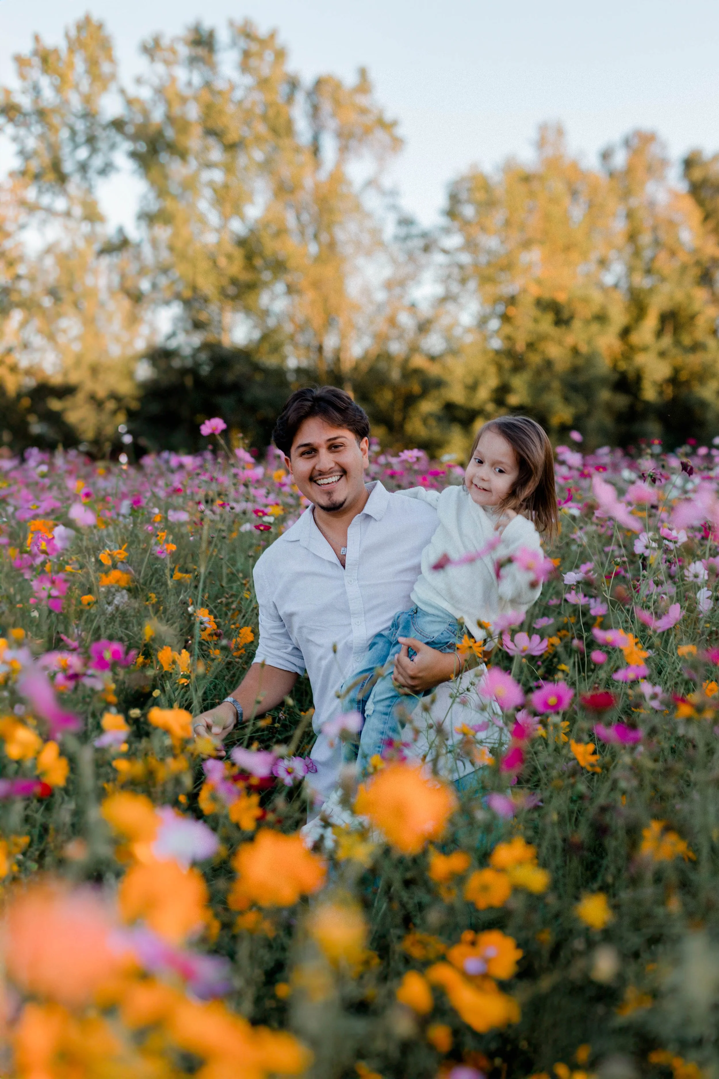 Josh Hill holding his daughter in a field of wildflowers