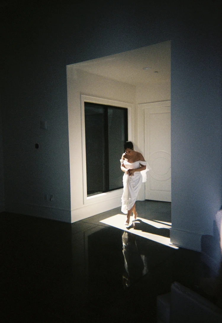 A bride walking through the light by a big window, shot on 35mm film