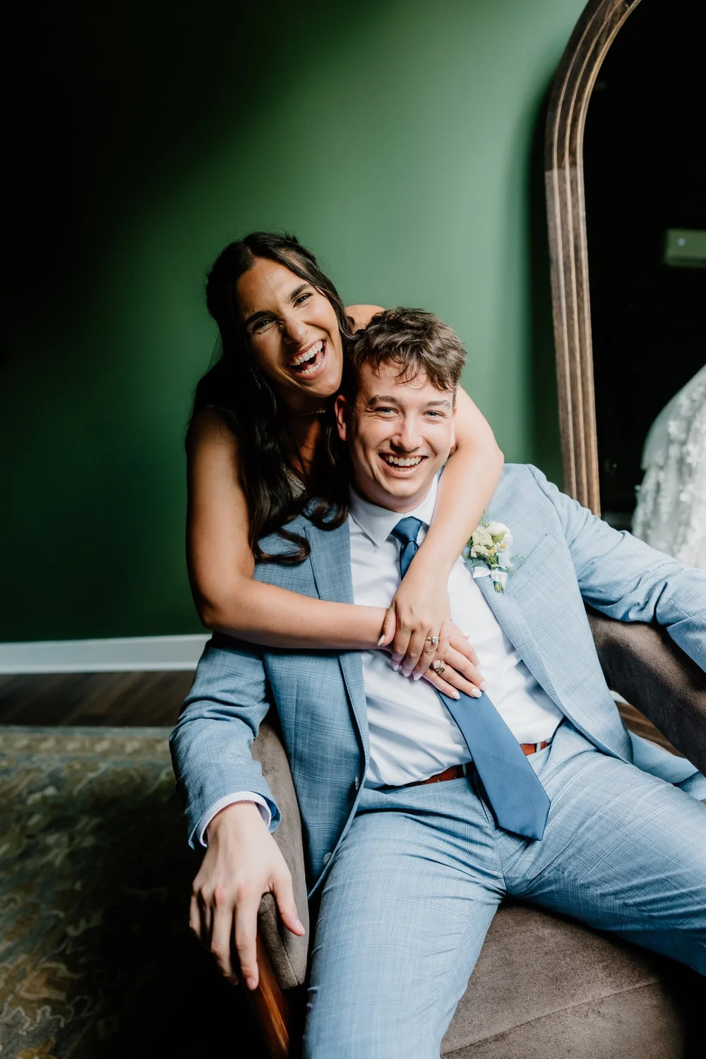 A couple laughing together on a green velvet couch