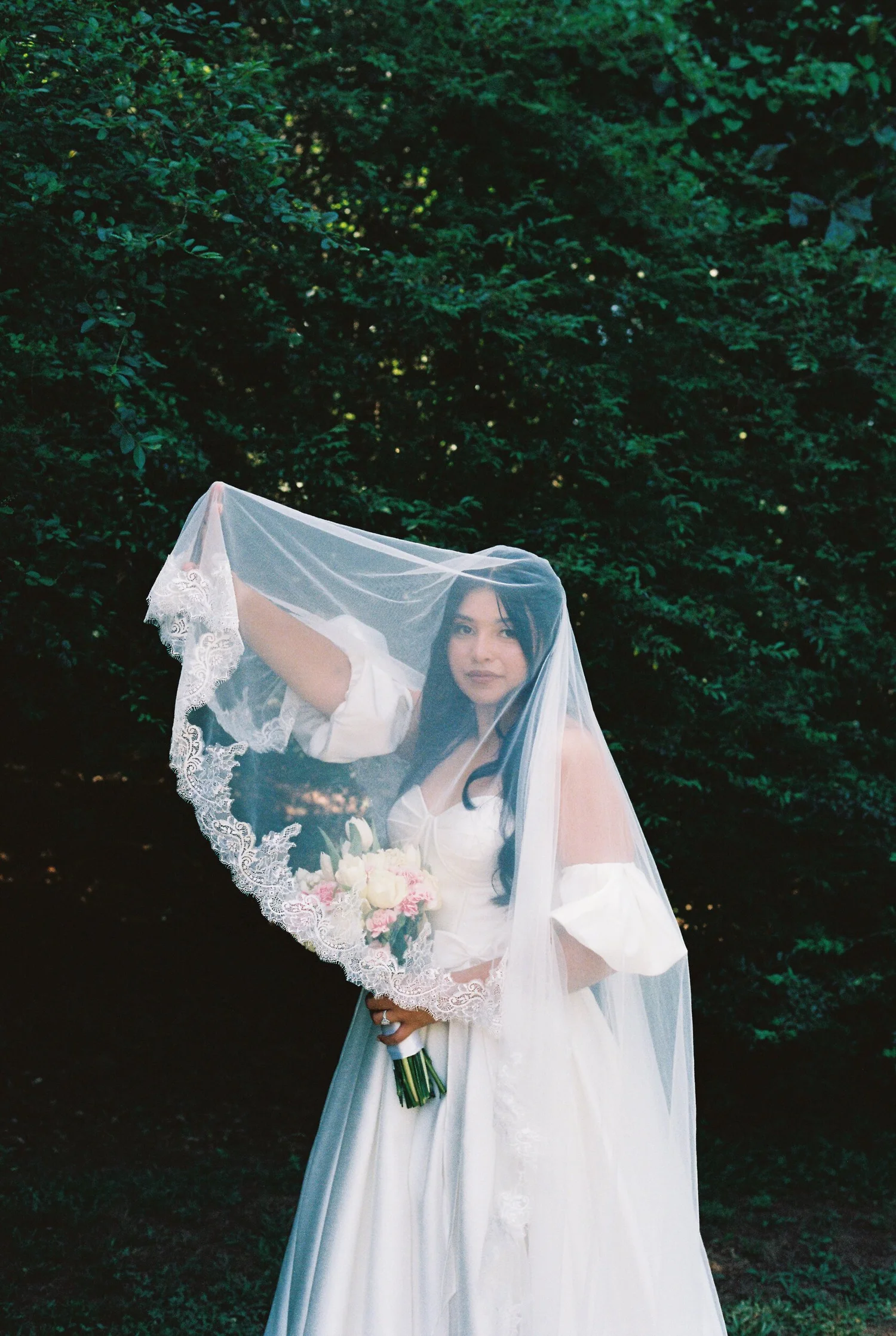 A bride holding her bouquet under her veil, shot on 35mm film