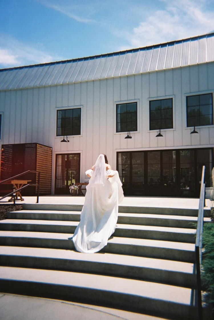 A bride walking up the steps in her veil, shot on 35mm film