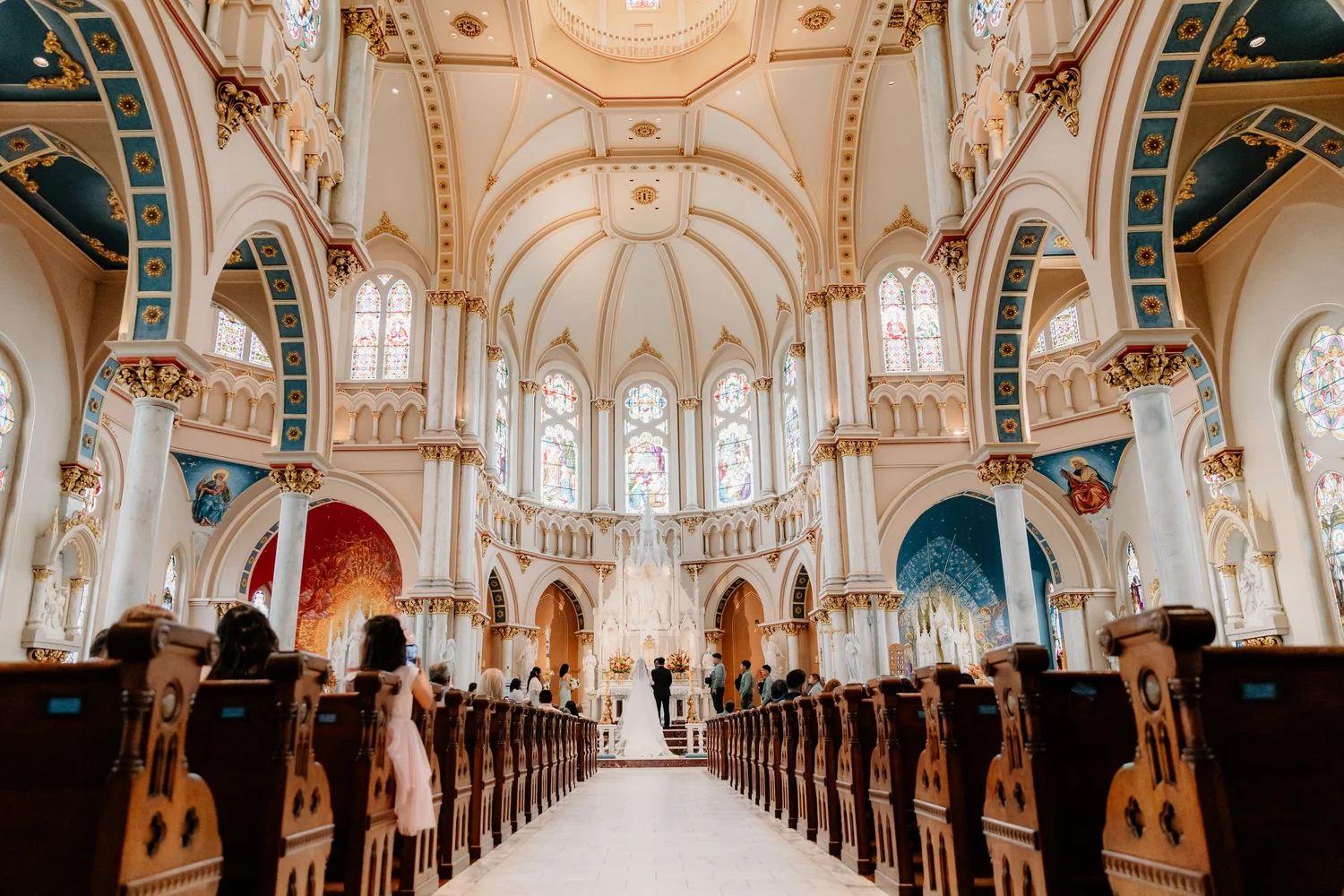 Catholic wedding ceremony seen down the aisle of a cathedral