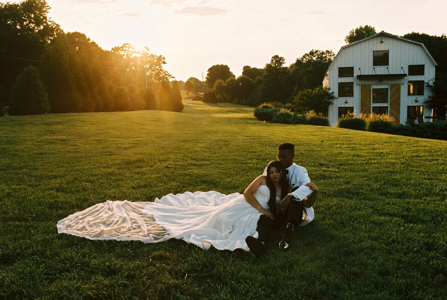 A couple sitting together on the lawn at golden hour, shot on 35mm film