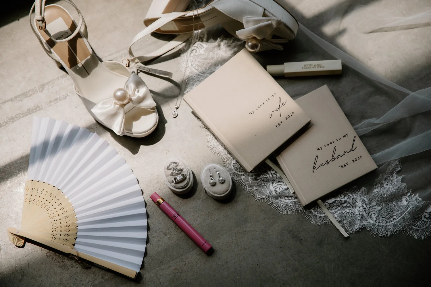 Bridal shoes, a hand fan and the invitation suite laid out on slate