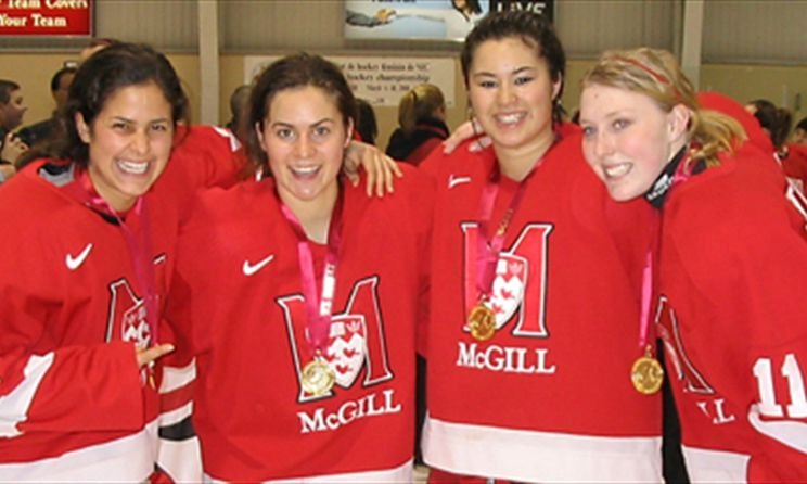 Lisa Zane (the author of this newsletter) and three of her teammates smiling and wearing gold medals after winning the CIS National Ice Hockey Championship. Each of the four women are wearing their red and white McGill Martlets jersey.