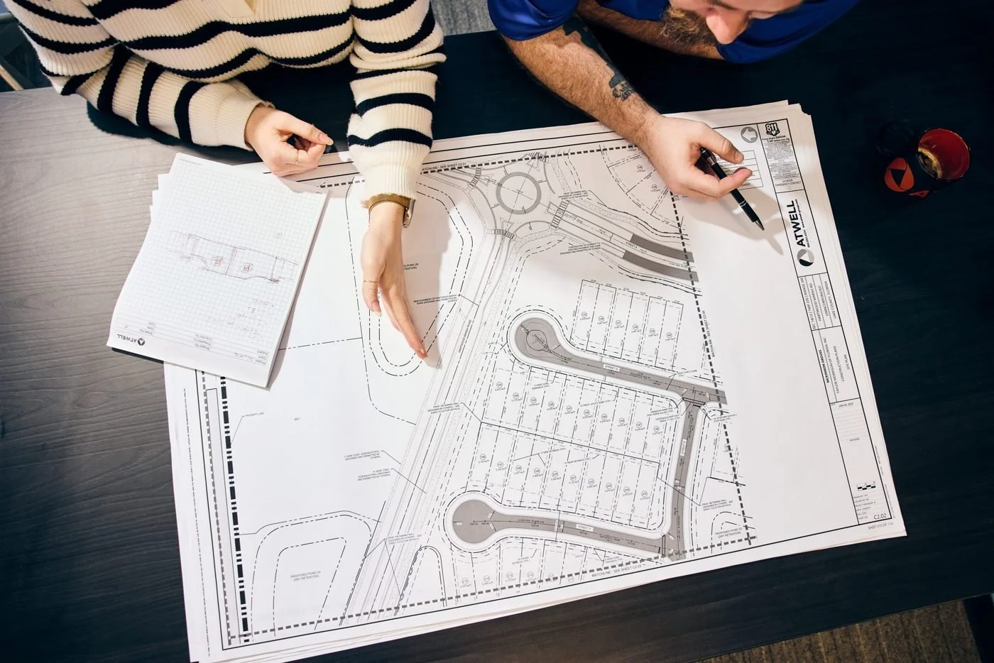 Two people mark up a neighborhood site plan on a conference table.