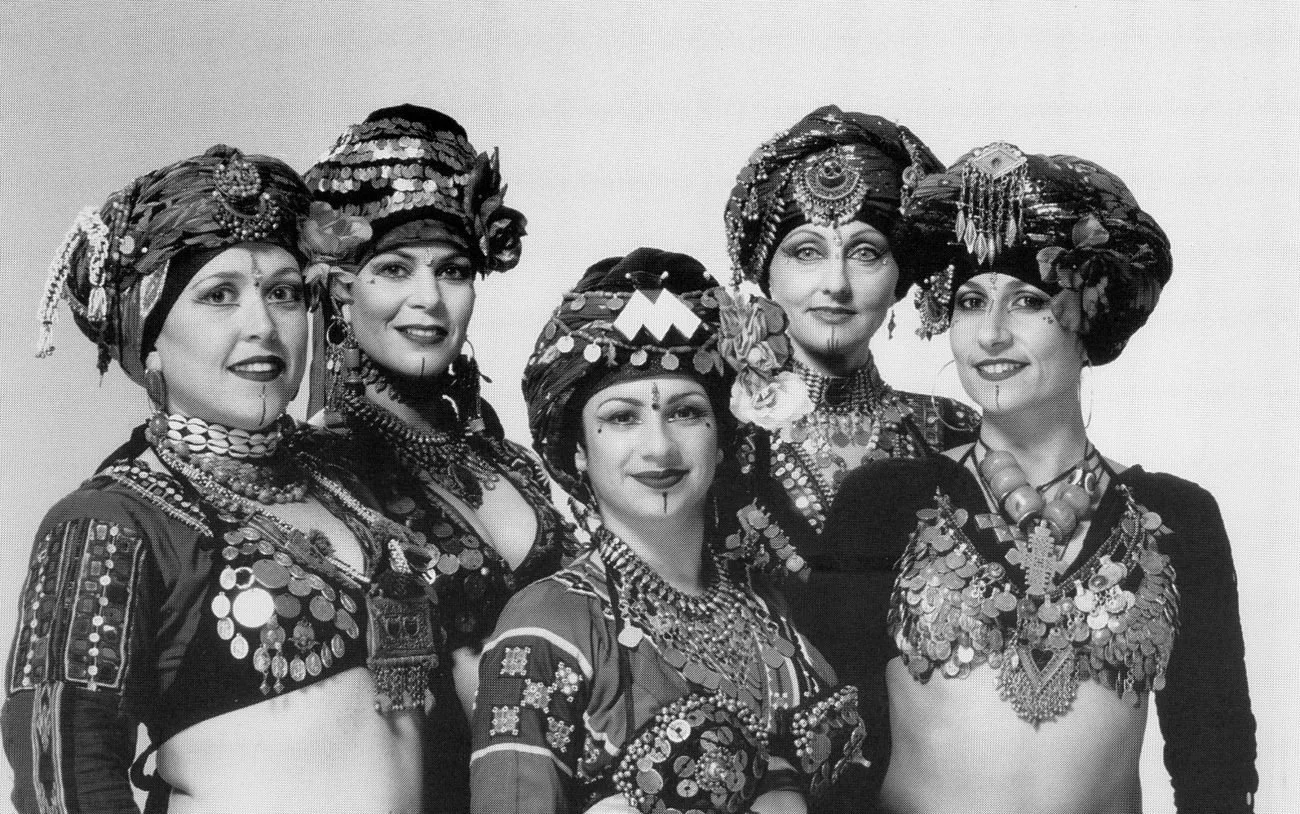 Black and white portrait of five FCBD® Style dancers in turbans, coin bras and jewelry, smiling together