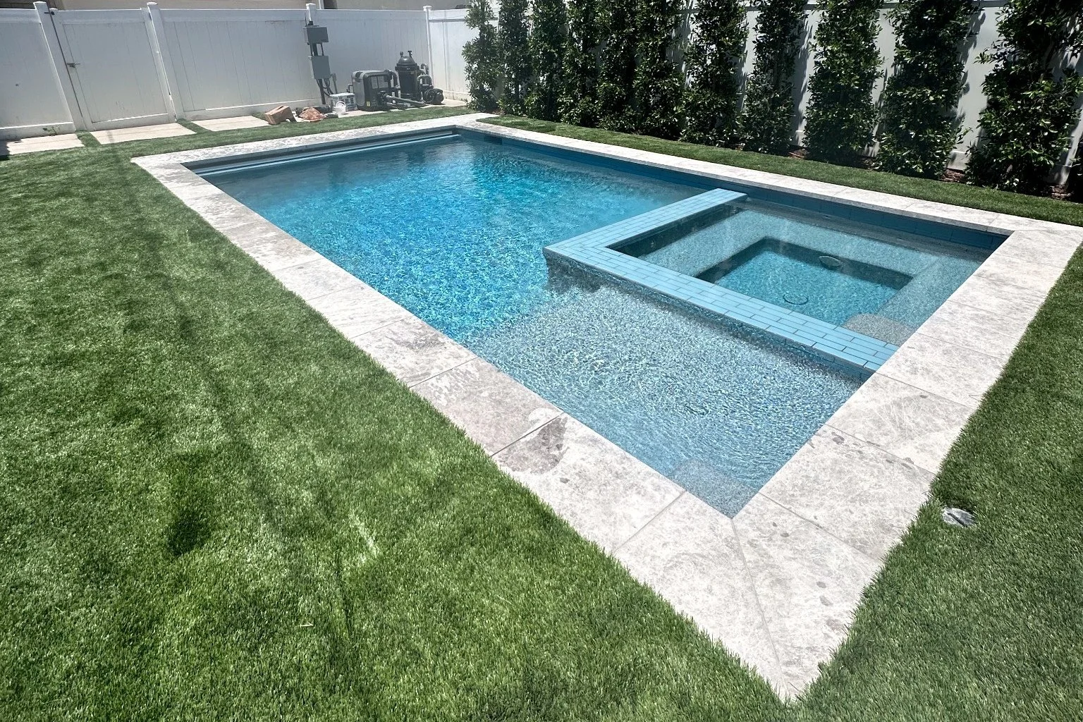 Hansen rectangular pool with an integrated square spa, light-colored coping, and surrounding lawn