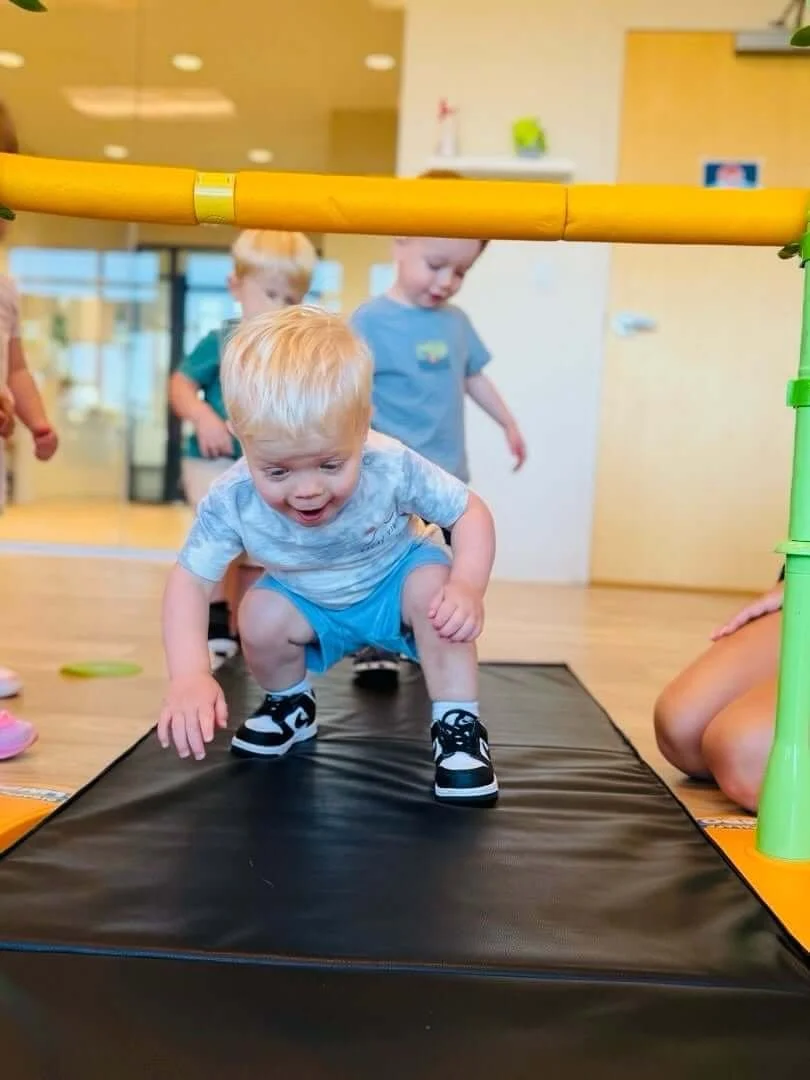 Toddler laughing as she crawls out of a play tunnel