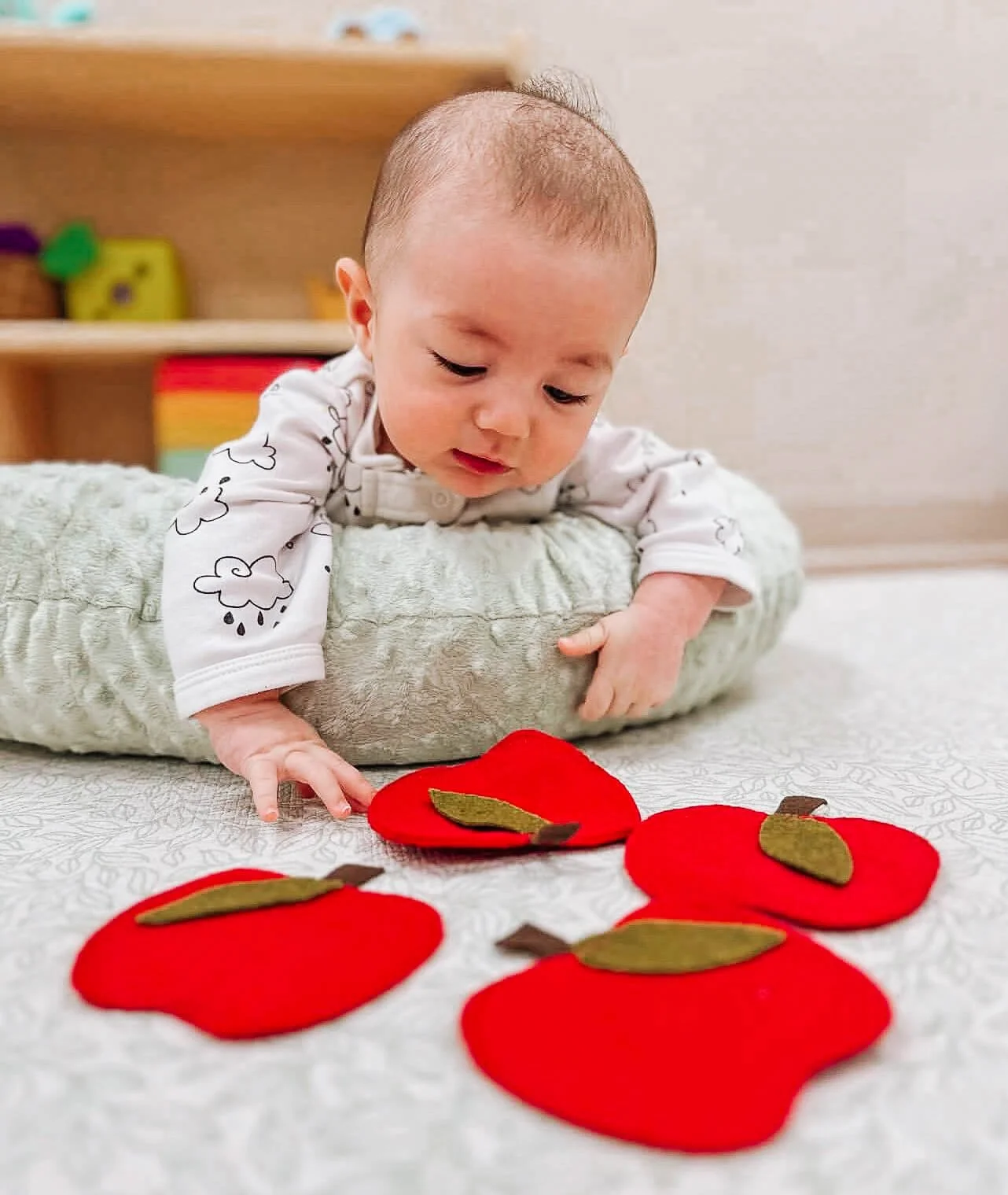 Baby doing tummy time with toy train cars