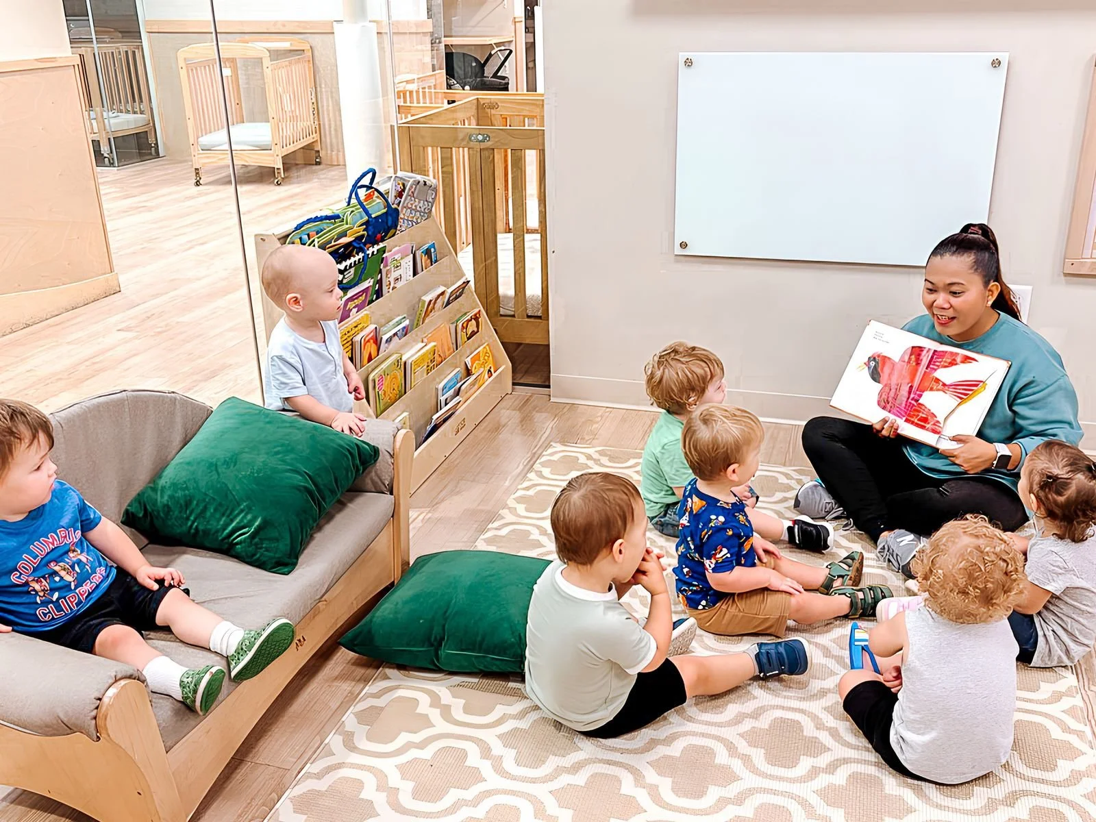 Teacher reading a picture book to a small group of toddlers