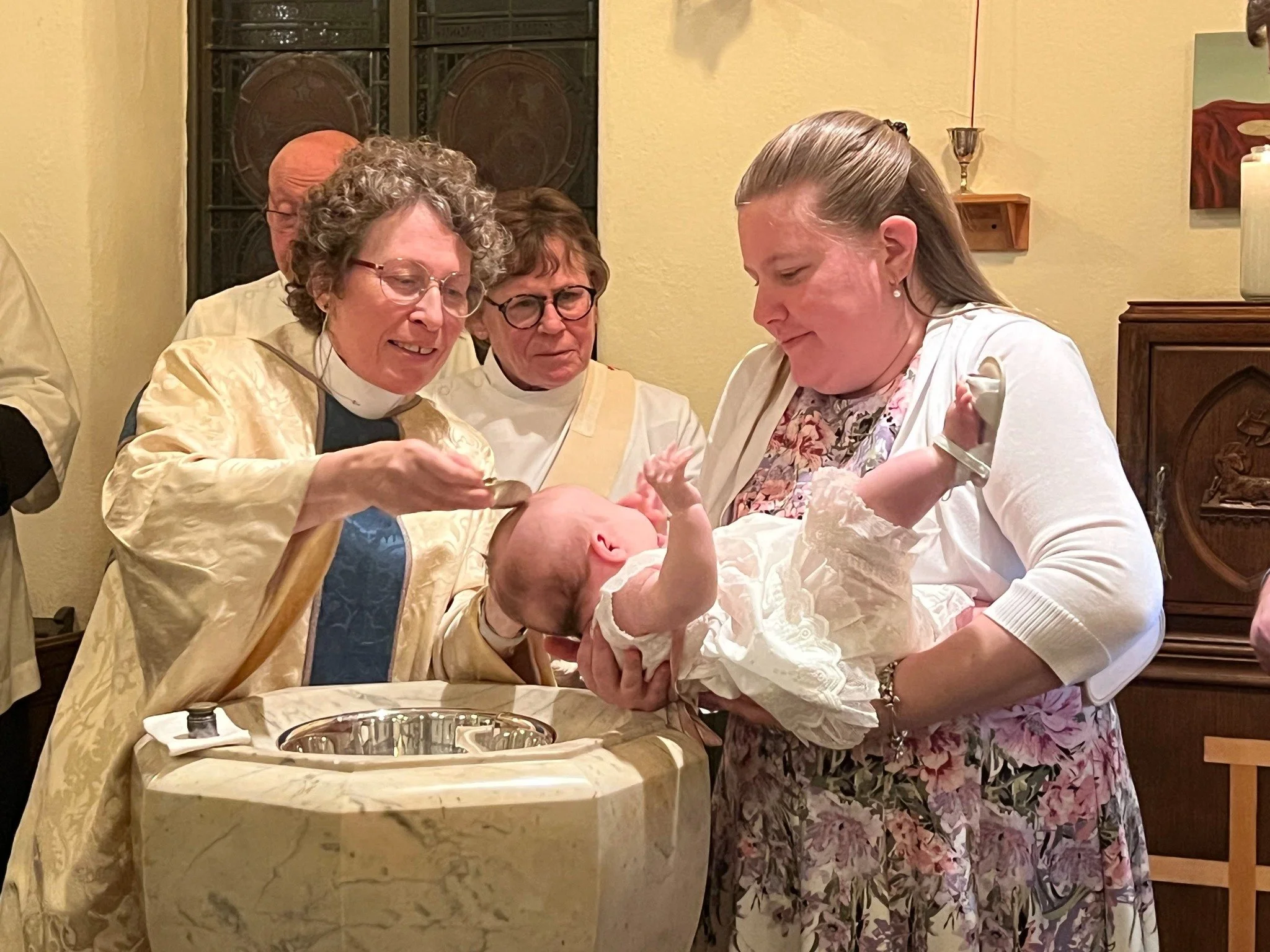 A priest pours water over a baby’s head at the baptismal font at St. Paul’s Cathedral.