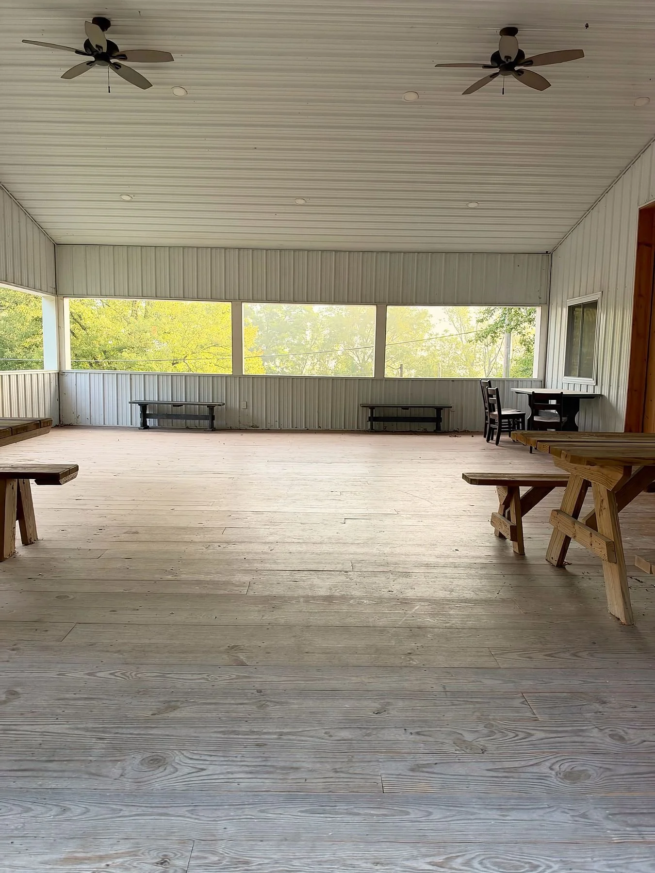 Inside the pavilion, with benches, picnic tables, and ceiling fans